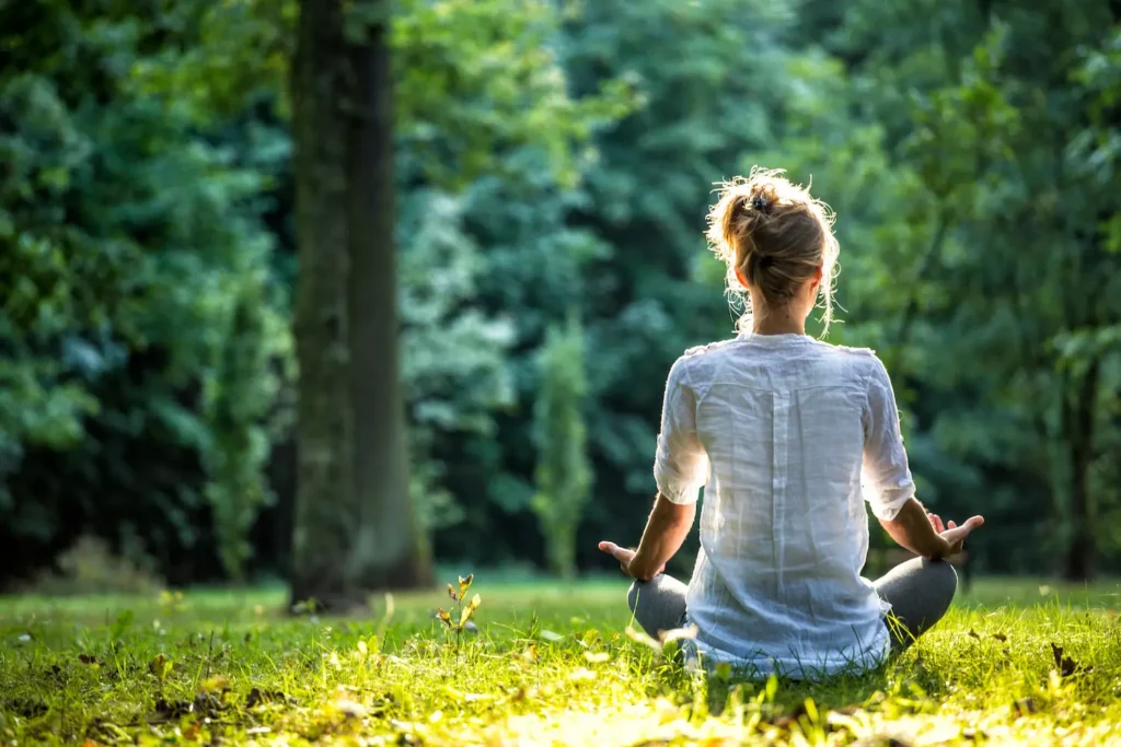 Woman meditating in the woods after therapy session with Strong Mind Psychiatry