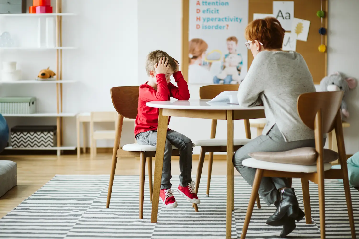 A boy with ADHD sitting at a table during a session with a professional pediatric psychiatrist