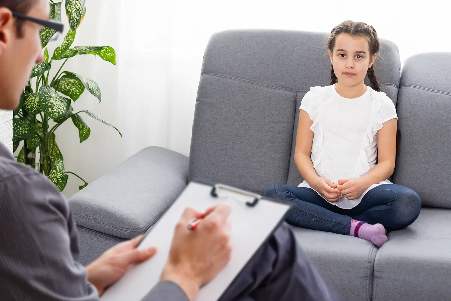 A child sitting on the couch in front of a psychiatrist during ADHD testing.