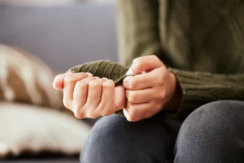 Close-up of anxious person fidgeting with sweater sleeves, showing symptoms of anxiety