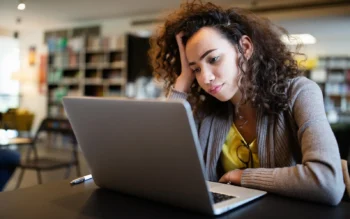 A student on her laptop in a library, struggling with ADHD 