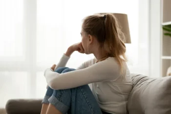 A woman sitting on a couch looking away with her hand on her face