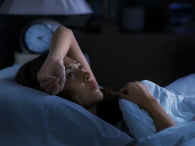 Woman laying in bed distressed over sleep anxiety problems.