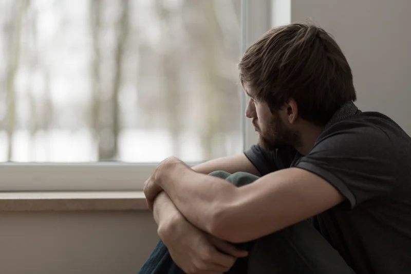 A person sitting on the floor staring out of their window